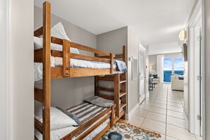 A hotel room with bunk beds, a small desk, a chair, and a view of the sea. - Thunder Beach🏍️! Rally, Recharge, Repeat! Calypso 2 • 19 Floors Above the Surf 🌊 (Panama City Beach)