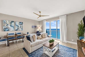 A living room with a sofa, coffee table, and artwork on the walls. - Enjoy Luxe King Mattress after Iron Man 💪Calypso II beachfront 19th Floor View! (Panama City Beach)