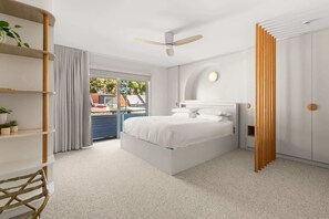 Een moderne slaapkamer met een groot bed, een plafondventilator en uitzicht door een glazen deur.