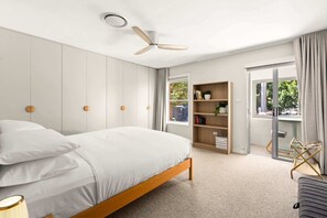 A bedroom with a bed, a ceiling fan, a bookshelf, and a sliding glass door leading to a balcony. - Designer 2BR Terrace | BBQ Garden near Moore Park (Redfern)