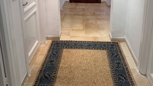 A hallway with a patterned rug, a wooden door, and white walls.