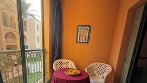 A balcony with a table and chairs, a view of buildings, and a door.