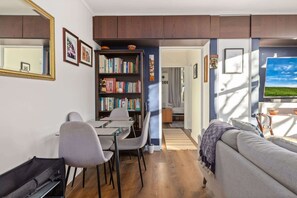 A modern living room with a sofa, a dining table with chairs, a bookshelf, and a large mirror. - Peaceful Hideaway 2-Bed Apartment Mosman (Mosman)