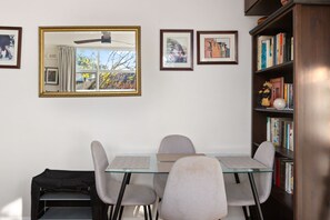 A room with a glass-top table, four chairs, a bookshelf, and framed pictures on the wall. - Peaceful Hideaway 2-Bed Apartment Mosman (Mosman)