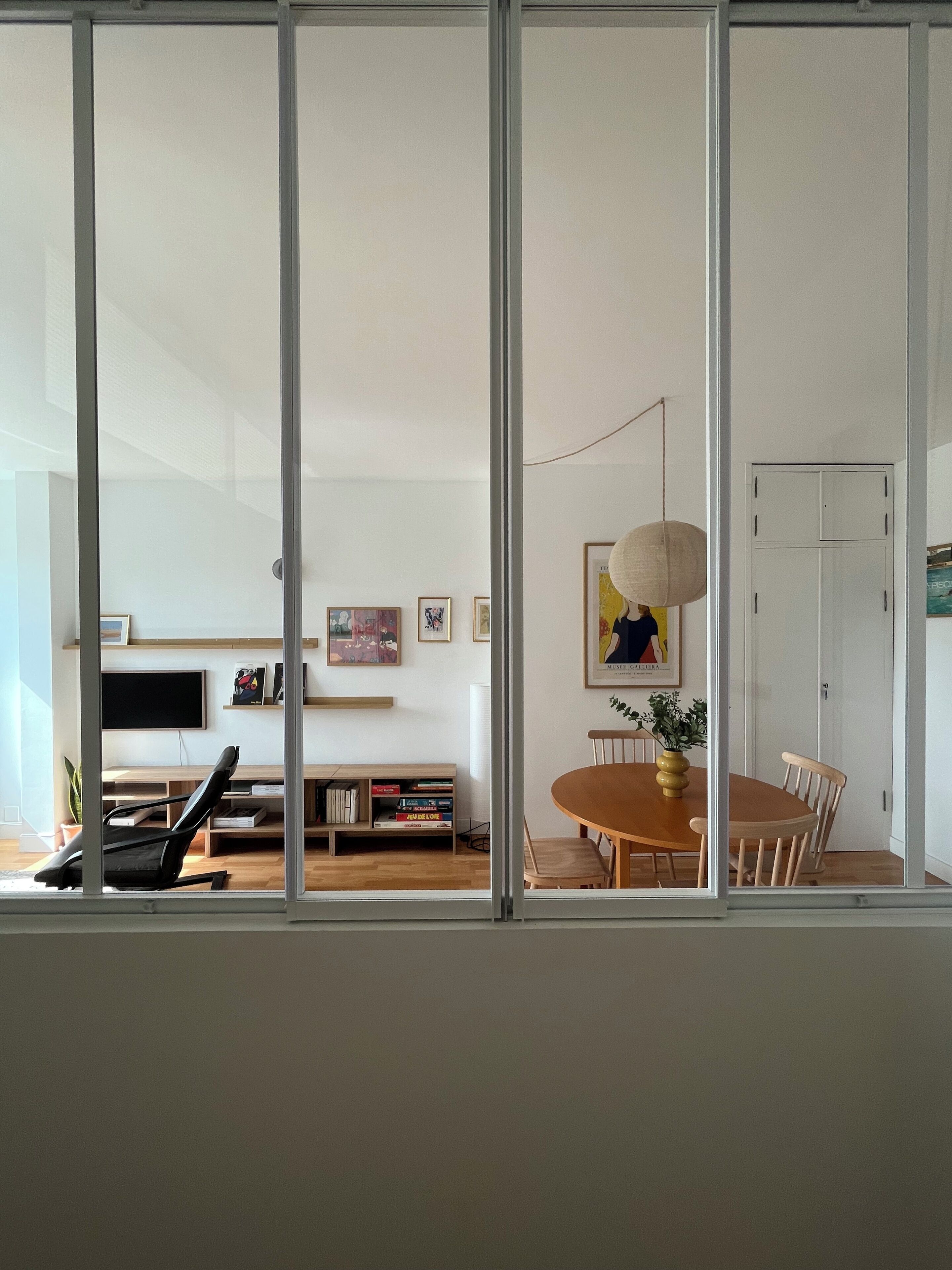 A modern living room with a dining area, a bookshelf, and a television.