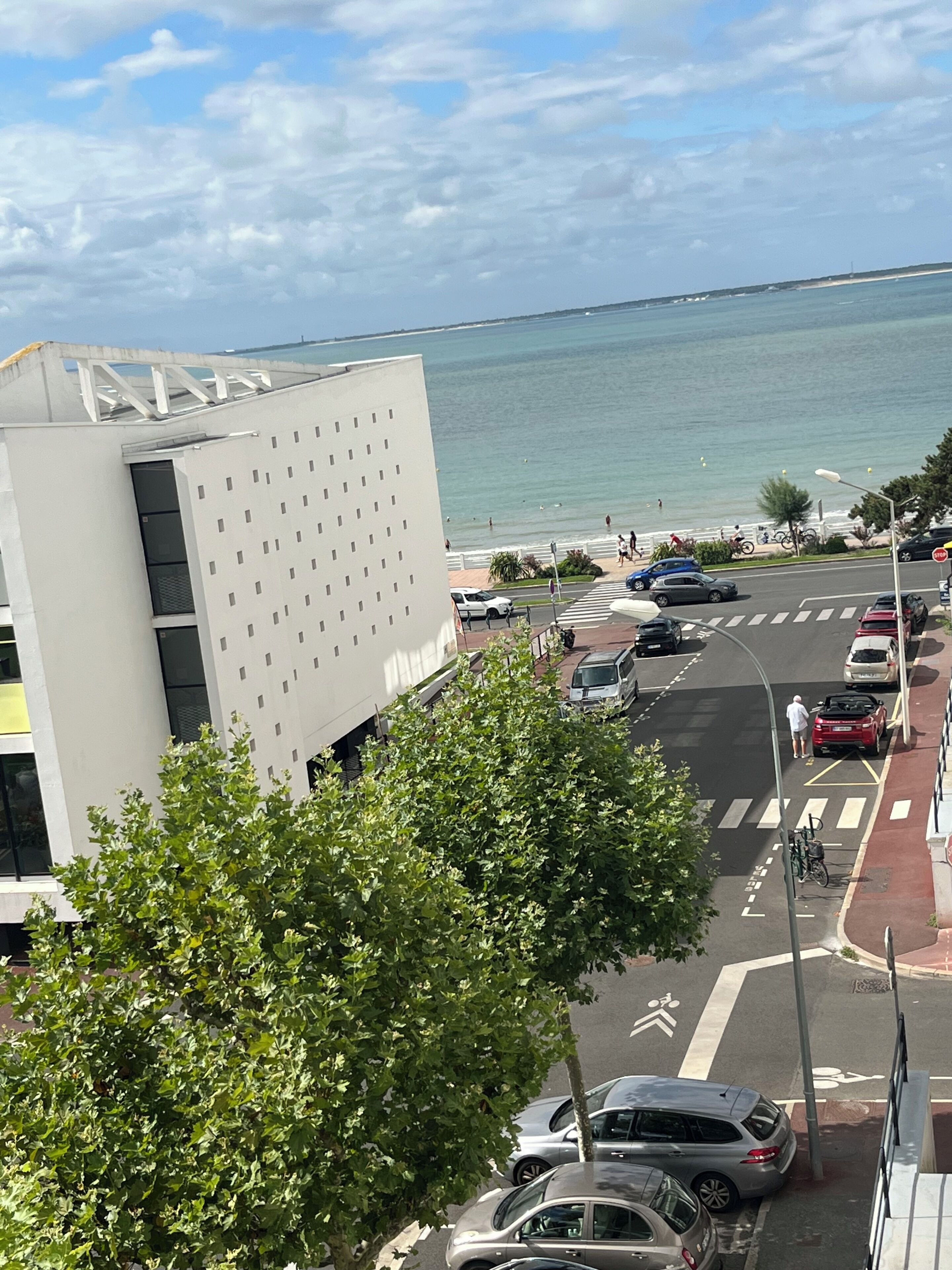 A modern building with a parking lot and a view of the sea.