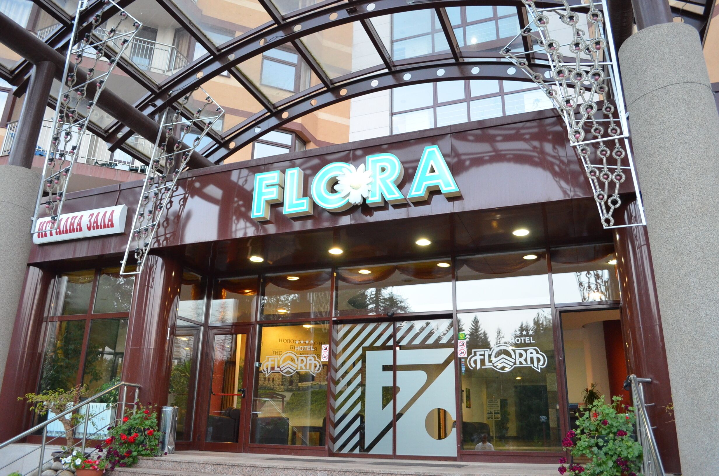 Entrada de hotel con un cartel llamativo que dice 'FLORA'.