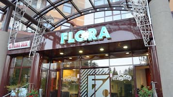 Entrada de hotel con un cartel llamativo que dice 'FLORA'.