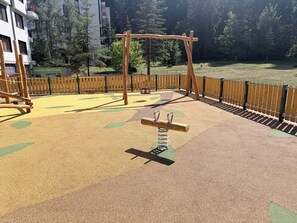 A playground with a wooden swing set and a seesaw.