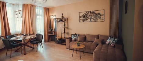 Una sala de estar con sofá, una mesa de comedor con sillas, una mesa de centro y una estantería.