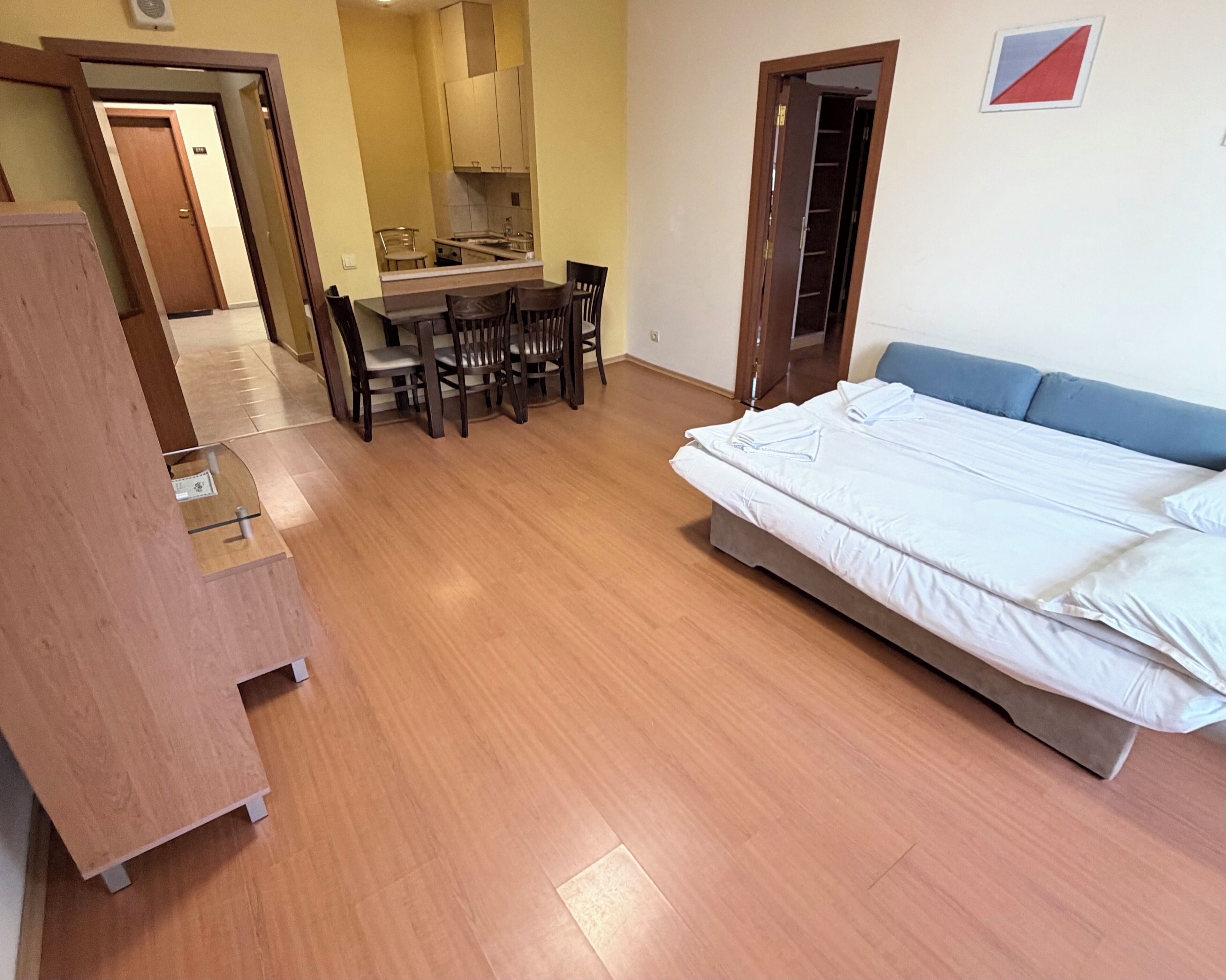 Un dormitorio con cama, una mesa de comedor con sillas y una kitchenette.