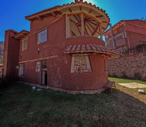 A two-story building with a unique architectural design, including a curved facade and a large circular window. - Country House in the Sacred Valley of the Incas: Pisac - Rinconada (Písac)