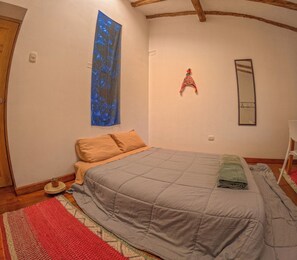 A bedroom with a bed, a wall-mounted mirror, a small decorative item, and a potted plant.