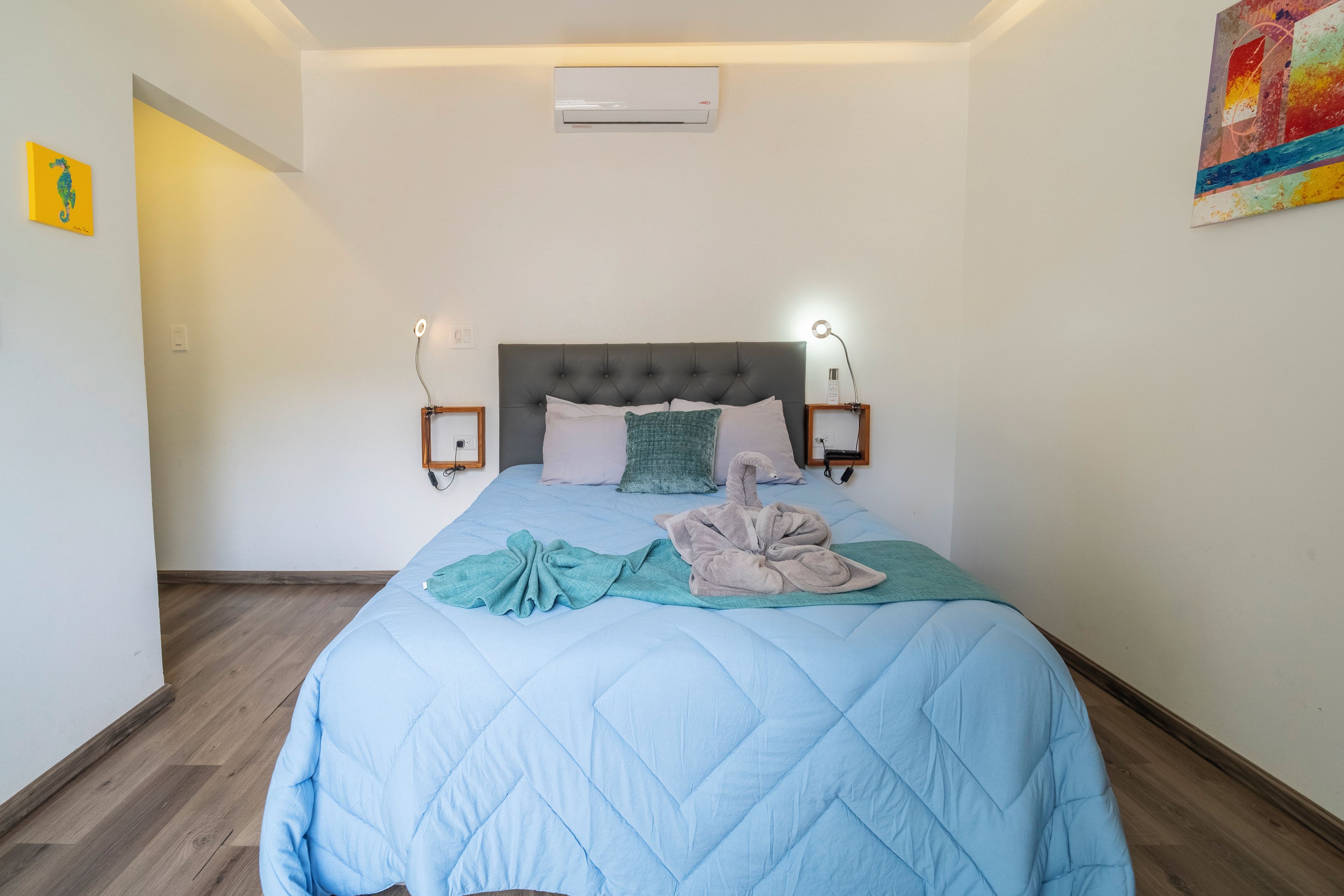 Un dormitorio con una cama, aire acondicionado de pared y un cuadro.