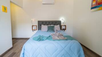 Un dormitorio con una cama, aire acondicionado de pared y un cuadro.