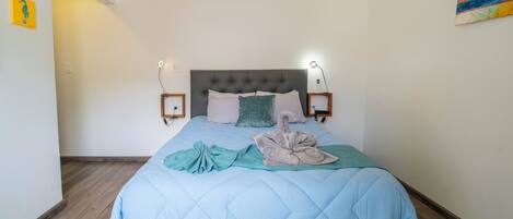 A bedroom with a bed, a wall-mounted air conditioner, and a painting.