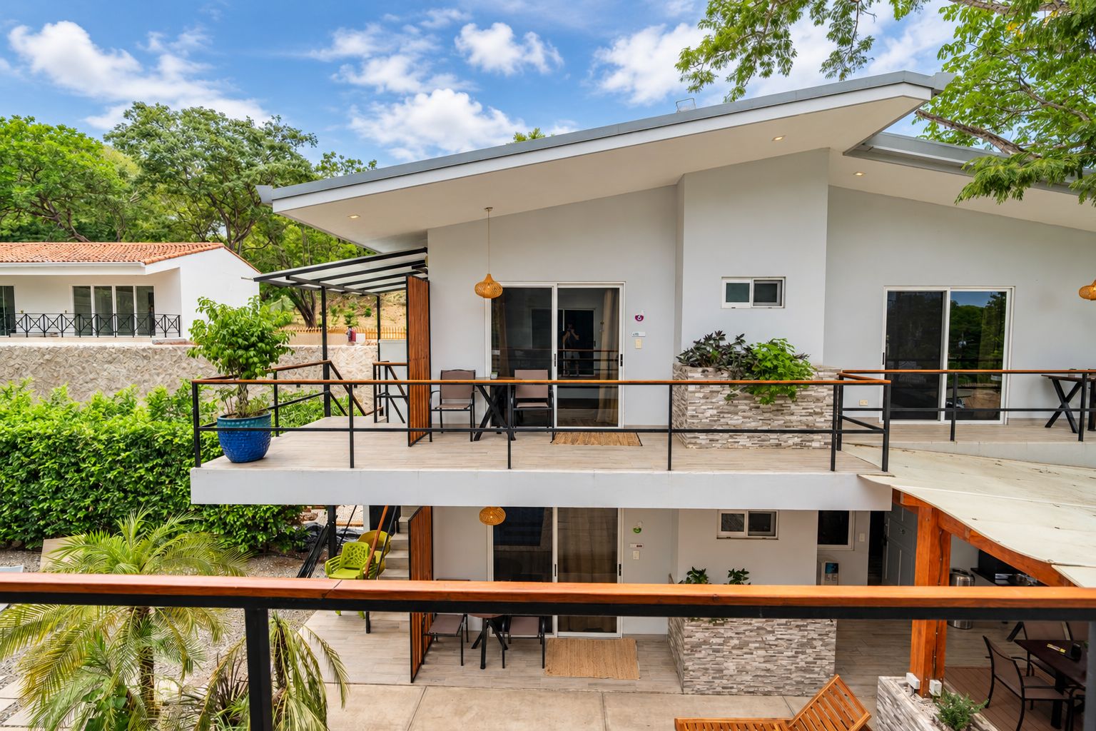 Una casa moderna de dos pisos con balcón, mobiliario exterior y fachada de piedra.