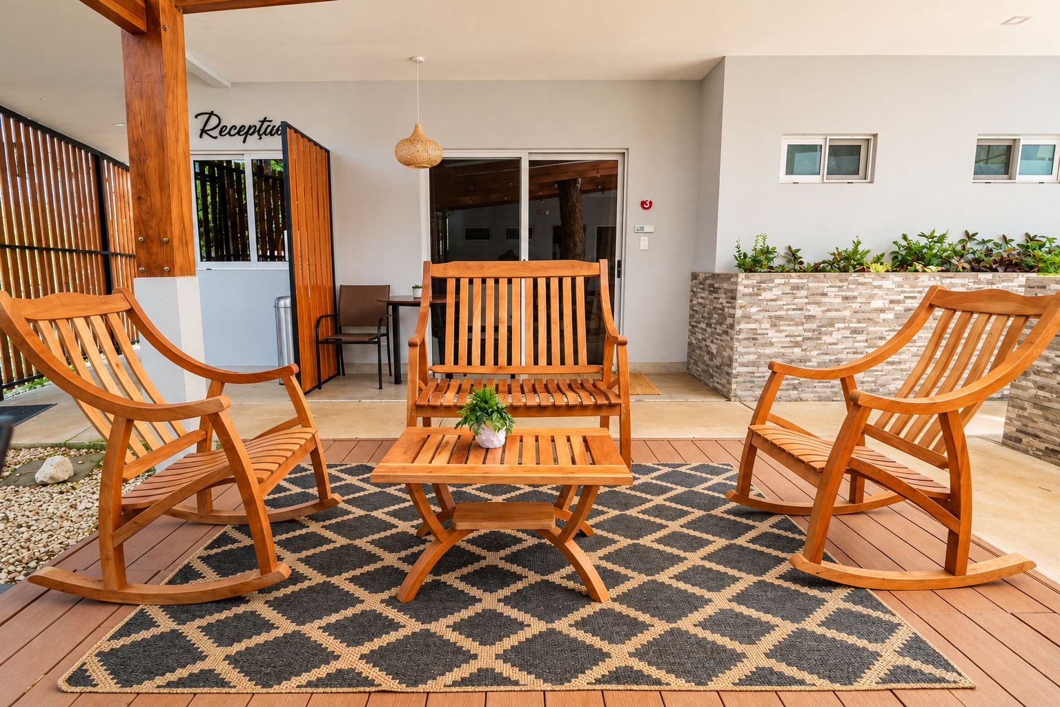 Ein Außenbereich mit Sitzgelegenheiten, darunter zwei Schaukelstühle und ein Tisch, einer Holz-Pergola und einem Empfangsbereich.