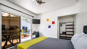A modern hotel room with a bed, a TV, a desk, and a balcony.