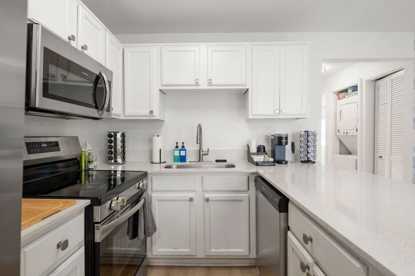 A modern kitchen with white cabinetry, stainless steel appliances, and a dishwasher.