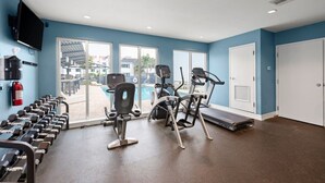 A gym with exercise equipment, a fire extinguisher, and a pool view.