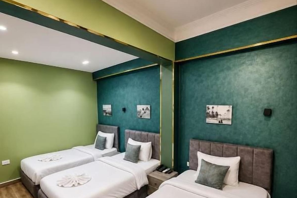 A hotel room with two beds, green walls, and a wooden floor.