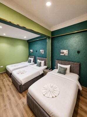 Habitación de hotel con dos camas, paredes verdes y suelo de madera.