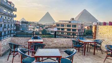 A rooftop terrace with tables and chairs, offering views of the pyramids.