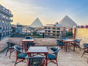 A rooftop terrace with tables and chairs, offering views of the pyramids.