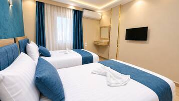 Habitación de hotel con dos camas, televisor y aire acondicionado.