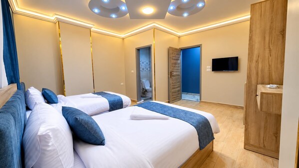 A hotel room with a bed, bedside tables, a wardrobe, a television, and a bathroom with a mirror and toilet.