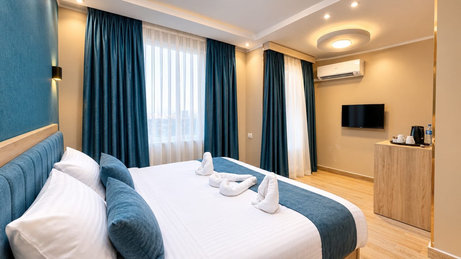 Une chambre d’hôtel avec un lit, une télévision, un bureau et une fenêtre avec des rideaux.