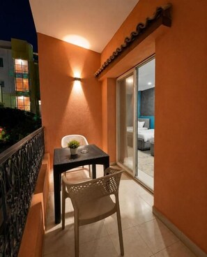 A balcony with a table and chairs, a potted plant, and a sliding glass door leading to a room. - Beko Pyramids Inn (Giza)
