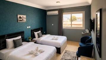 A hotel room with two beds, a desk, a chair, a TV, and a window with a view.