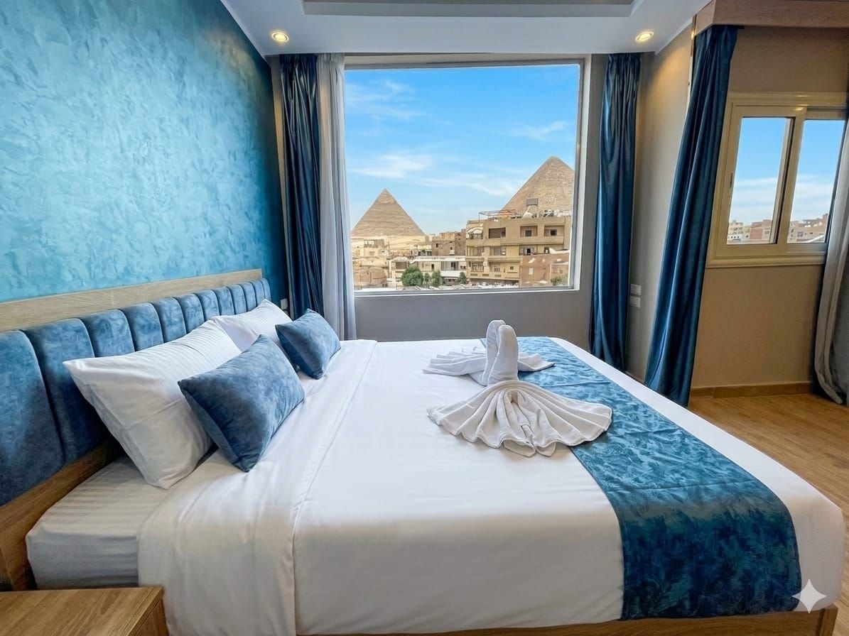 A hotel room with a bed, a view of pyramids, and curtains.