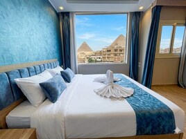 Habitación de hotel con cama, vista a las pirámides y cortinas.