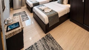 Quarto de hotel com duas camas, uma escrivaninha com computador, guarda-roupa e janela com cortinas.