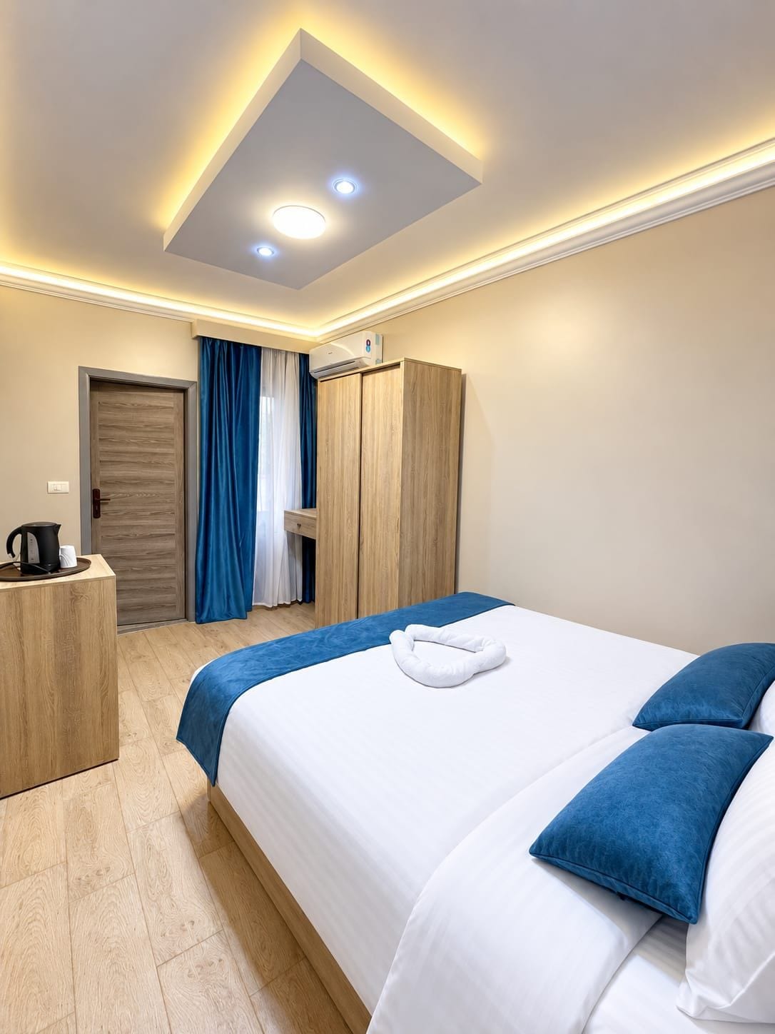 A hotel room with a bed, bedside table, and a wardrobe.