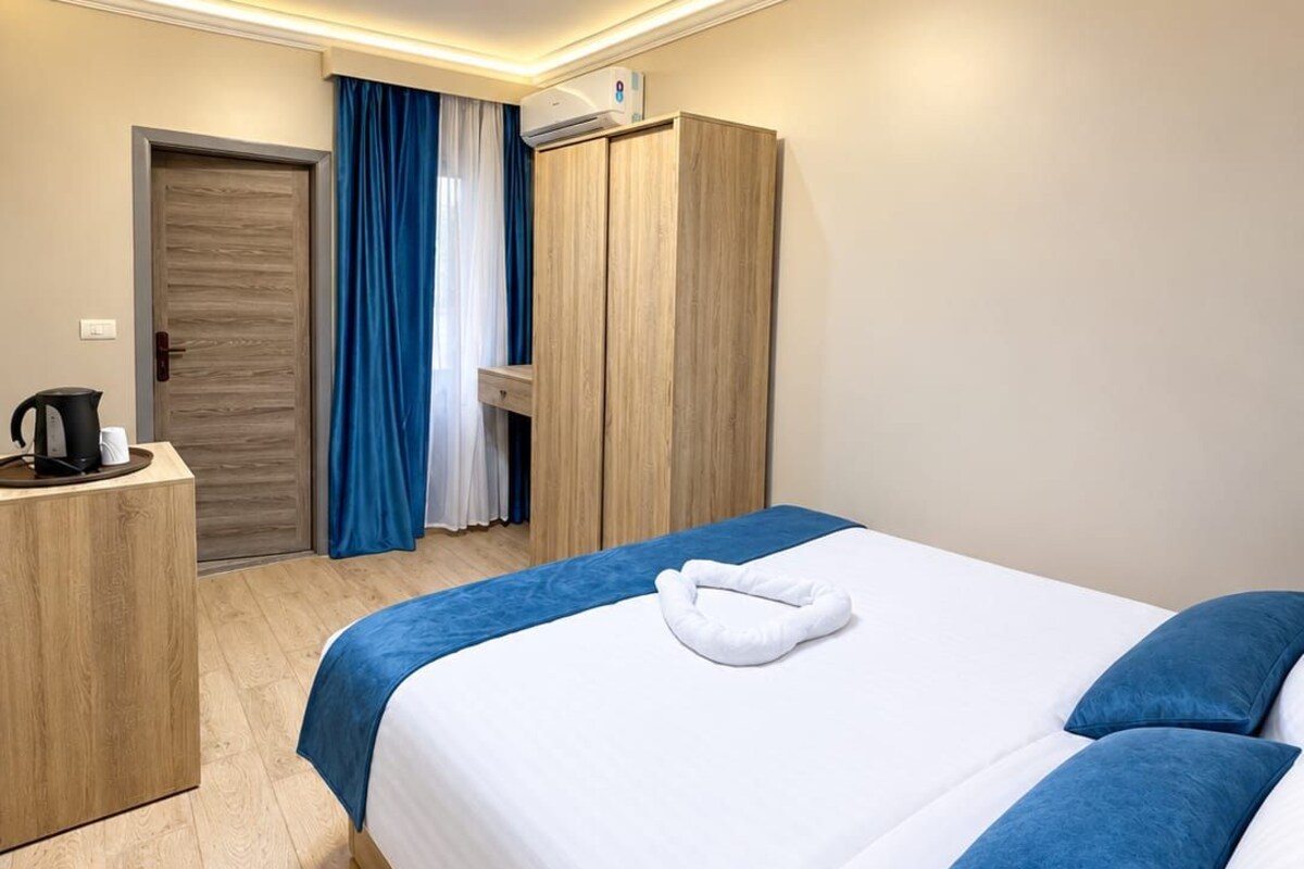 A hotel room with a bed, bedside table, and a wardrobe.