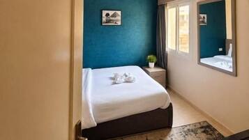 A hotel room with a bed, a bedside table, a mirror, and a door marked with the number 107.