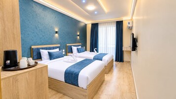 A hotel room with two beds, a coffee maker, and a TV on a wooden side table.