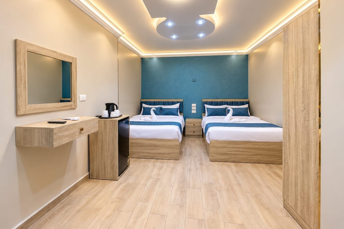 A hotel room with two beds, a wooden dresser, a mirror, and a ceiling with recessed lighting.