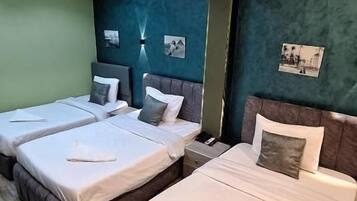 A hotel room with two beds, a wooden floor, and a green accent wall.