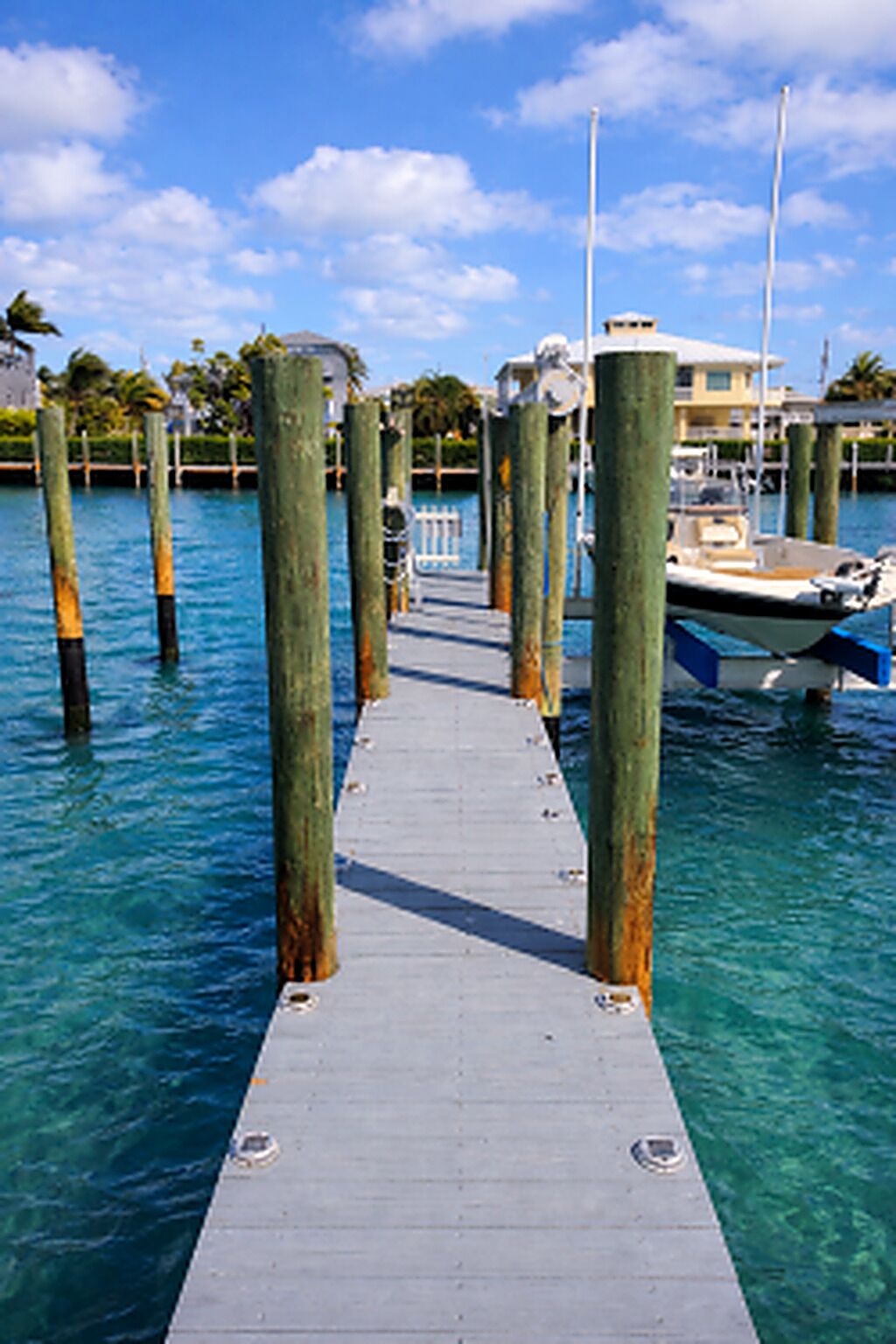 A pier leading to a dock with boats, surrounded by calm water and clear skies.