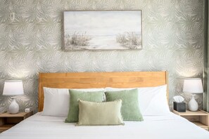 A bed with a wooden headboard, two bedside tables with lamps, and a wall-mounted painting of a beach scene. - Palm Luxury Huge 2br/2ba Pool/Gym Downtown Tampa (Tampa)