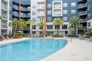 A modern multi-story building with a central swimming pool, surrounded by palm trees and outdoor seating. - Palm Luxury Huge 2br/2ba Pool/Gym Downtown Tampa (Tampa)