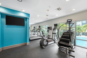 A gym with treadmills, elliptical machines, and a stair climber, with a pool visible through the windows. - Palm Luxury Huge 2br/2ba Pool/Gym Downtown Tampa (Tampa)
