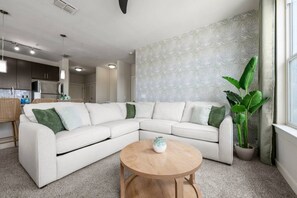 A modern living room with a sectional sofa, a round wooden coffee table, and a large potted plant. - Palm Luxury Huge 2br/2ba Pool/Gym Downtown Tampa (Tampa)