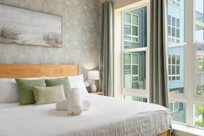 A hotel room with a large bed, a headboard, a painting on the wall, and a view of buildings through the window. - Palm Luxury Huge 2br/2ba Pool/Gym Downtown Tampa (Tampa)