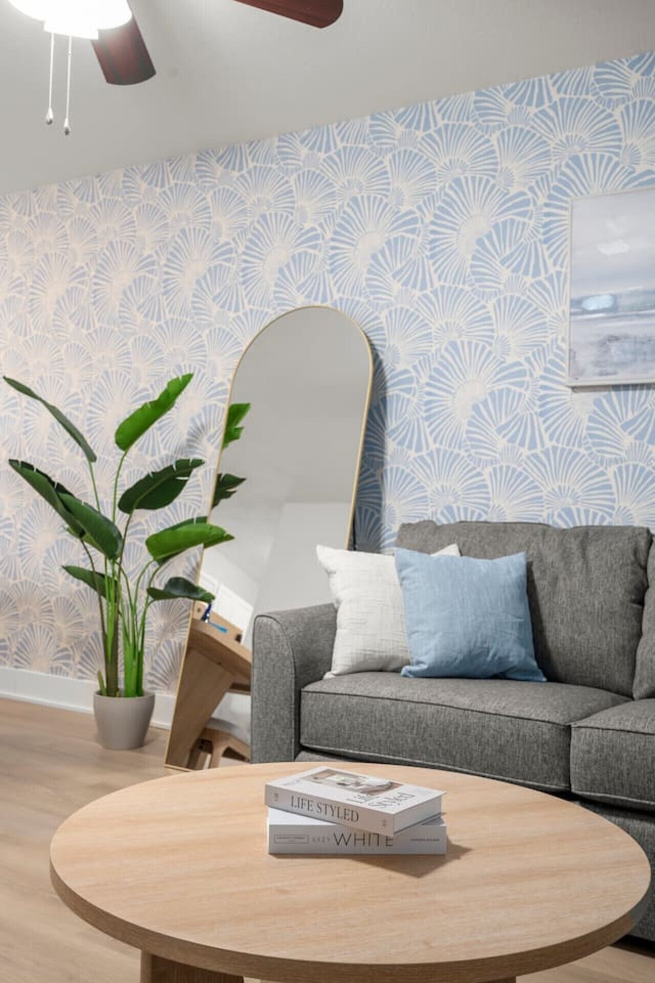 A modern living room with a grey sofa, a round wooden coffee table, and a potted plant.